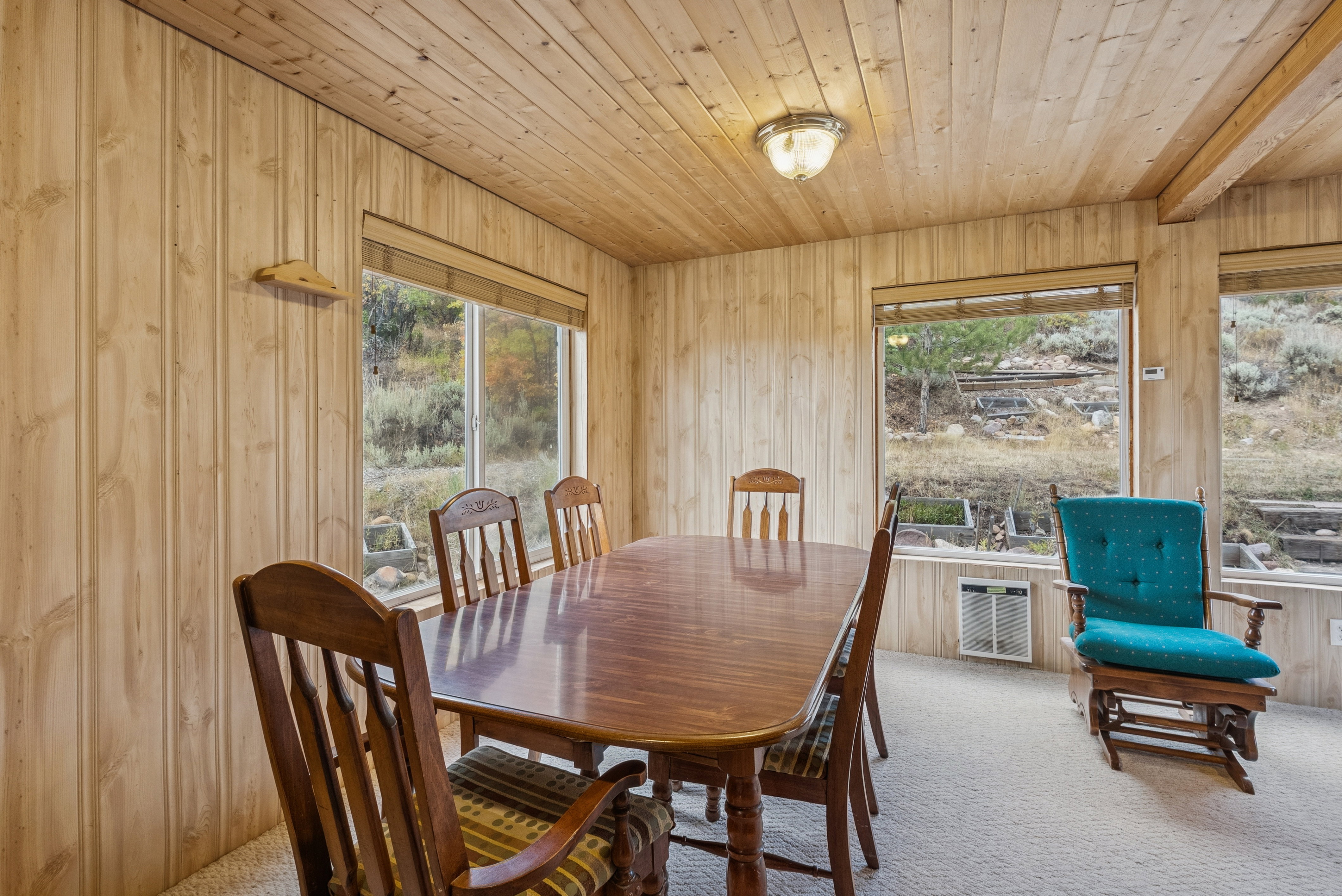 Dining space featuring wood walls, carpet floors, wooden ceiling, healthy amount of natural light, and heating unit