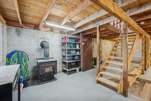 Unfinished below grade area with a wood stove and stairs