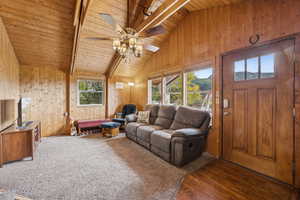 Living area featuring wooden walls, wooden ceiling, and dark wood-type flooring