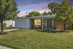 Mid-century inspired home featuring concrete block siding, driveway, a porch, and a garage