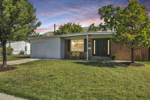 Mid-century modern home with concrete block siding, driveway, covered porch, and a garage