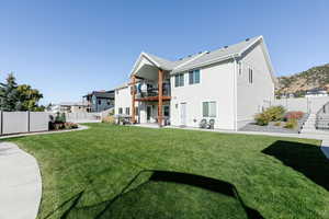 Back of property with a balcony, a fenced backyard, and a patio
