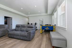 Living area featuring a tray ceiling, recessed lighting, and light wood-style floors