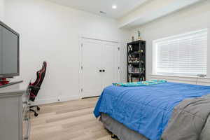 Bedroom with light wood-style flooring, recessed lighting, an office area, and a closet