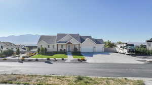 View of front facade with concrete driveway, a mountain view, a garage, and a front lawn