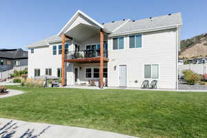 Back of property featuring a patio area, a lawn, and a balcony