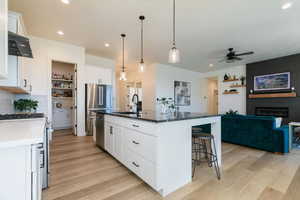 Kitchen featuring white cabinetry, open floor plan, recessed lighting, stainless steel appliances, and dark stone countertops