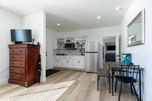 Kitchen featuring stainless steel appliances, white cabinetry, light wood-style flooring, tasteful backsplash, and recessed lighting