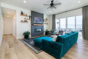 Living room with light wood finished floors, recessed lighting, a large fireplace, a ceiling fan, and a mountain view