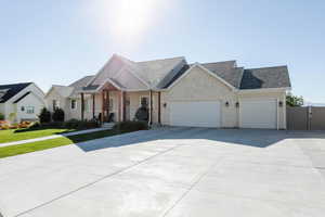 View of front of home featuring covered porch, concrete driveway, a garage, stone siding, and a front lawn