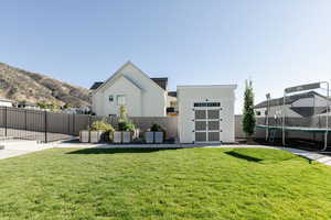 Back of property with a shed, board and batten siding, a trampoline, a fenced backyard, and a patio