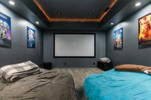 Home theater featuring a raised ceiling, carpet flooring, and recessed lighting