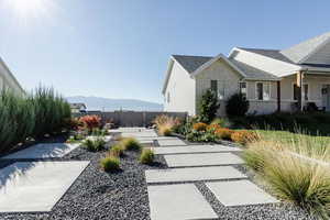 View of side of home with stone siding, a mountain view, and roof with shingles