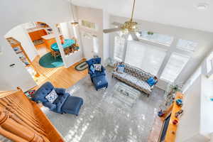 Living room featuring high vaulted ceiling, a ceiling fan, wood finished floors, and arched walkways