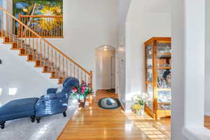 Foyer entrance featuring arched walkways, wood finished floors, a high ceiling, and stairs