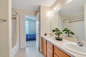 Bathroom featuring shower / bath combination with curtain, double vanity, and ensuite bath
