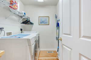 Laundry area with light wood-type flooring and washing machine and dryer