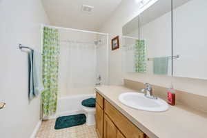 Full bath with shower / tub combo, vanity, and a textured ceiling