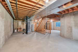 Unfinished below grade area featuring secured water heater, stairway, and heating unit
