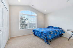 Carpeted bedroom featuring lofted ceiling, recessed lighting, and a closet
