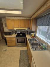 Kitchen featuring appliances with stainless steel finishes, light countertops, brown cabinetry, and under cabinet range hood