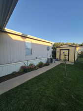 View of side of property featuring a yard and a storage shed