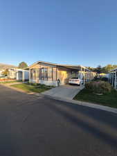 Manufactured / mobile home with a carport, driveway, a front yard, and a sunroom
