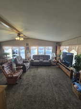 Carpeted living room featuring ceiling fan and a textured ceiling