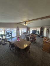 Dining area featuring dark colored carpet, a textured ceiling, and ceiling fan