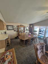 Dining space featuring lofted ceiling, carpet flooring, and a textured ceiling