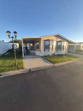 Manufactured / mobile home with an attached carport, a front lawn, and driveway