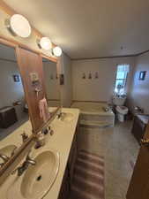 Bathroom with a garden tub, a textured ceiling, radiator, double vanity, and light tile patterned floors