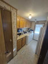 Washroom with wallpapered walls, a textured ceiling, washer and dryer, and cabinet space