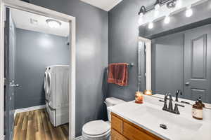 Bathroom featuring dark wood-style floors, vanity, washer / clothes dryer, and a textured ceiling
