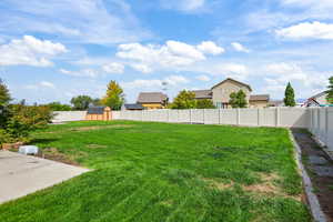 Fenced backyard featuring a storage unit
