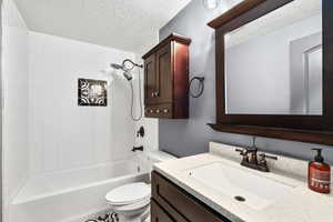 Bathroom featuring a textured ceiling,  shower combination, and vanity
