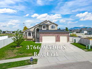 View of front of house with concrete driveway, stucco siding, brick siding, a mountain view, and roof with shingles