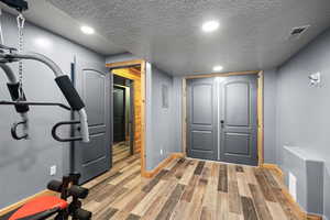Workout room with a textured ceiling, wood finished floors, and recessed lighting