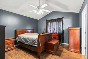 Bedroom with vaulted ceiling, dark wood finished floors, a ceiling fan, and a textured ceiling