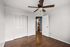 Unfurnished bedroom featuring dark wood-style flooring, ceiling fan, and a closet