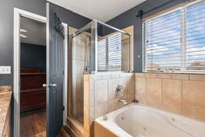 Bathroom with a shower stall, a whirlpool tub, a textured ceiling, and wood finished floors
