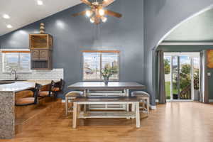 Dining room featuring light wood-style floors, plenty of natural light, arched walkways, recessed lighting, and high vaulted ceiling