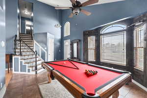 Playroom featuring a towering ceiling, pool table, ceiling fan, and dark tile patterned flooring