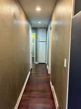 Corridor featuring a textured wall and dark wood-style floors