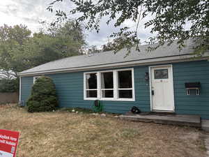 View of front of house with a front lawn and roof with shingles