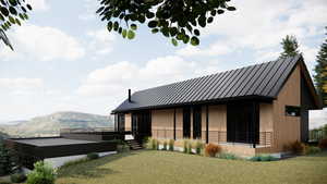 Back of house with a standing seam roof, a deck with mountain view, a metal roof, and a yard