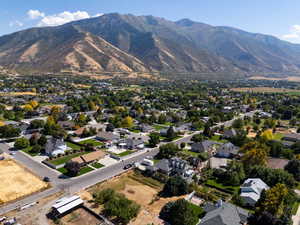 Aerial view of property and surrounding area featuring mountains and nearby suburban area