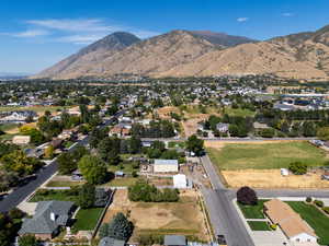 Aerial view of property and surrounding area featuring a mountain backdrop and nearby suburban area