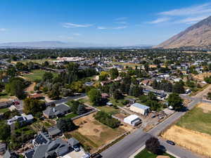 Aerial view of property and surrounding area featuring mountains and nearby suburban area