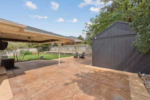 Fenced backyard with a patio and a storage unit
